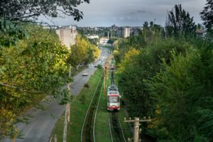 Aerial photograph of tram lines running through a lush cityscape with trees and buildings under a cloudy sky.