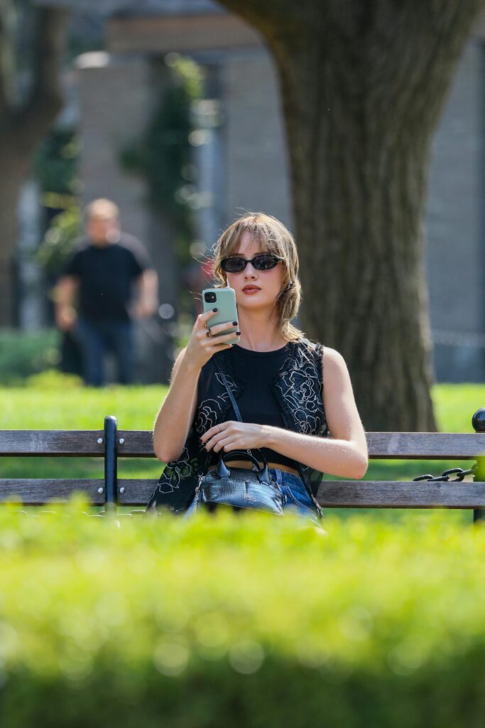 pexels-photo-12004637-12004637 Young woman wearing sunglasses using smartphone on park bench on a sunny day.