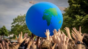 A vibrant scene of people raising hands to a large inflatable globe at a public event in Berlin.