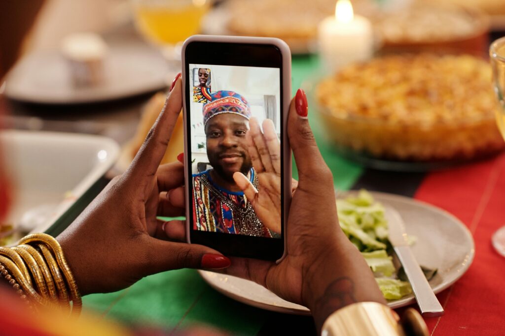 pexels-photo-6193431-6193431 A person uses a smartphone for a festive video call during a Kwanzaa celebration.