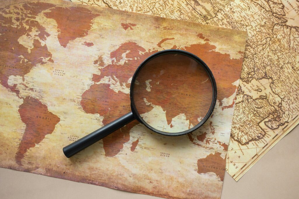 pexels-photo-7412013-7412013 A top view of a vintage world map with a magnifying glass highlighting regions for exploration.