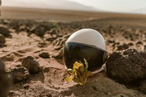 Close-up of an astronaut helmet on rocky desert terrain, evoking alien exploration.