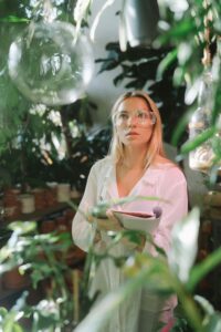 Focused female botanist conducting research amidst lush greenhouse plants.