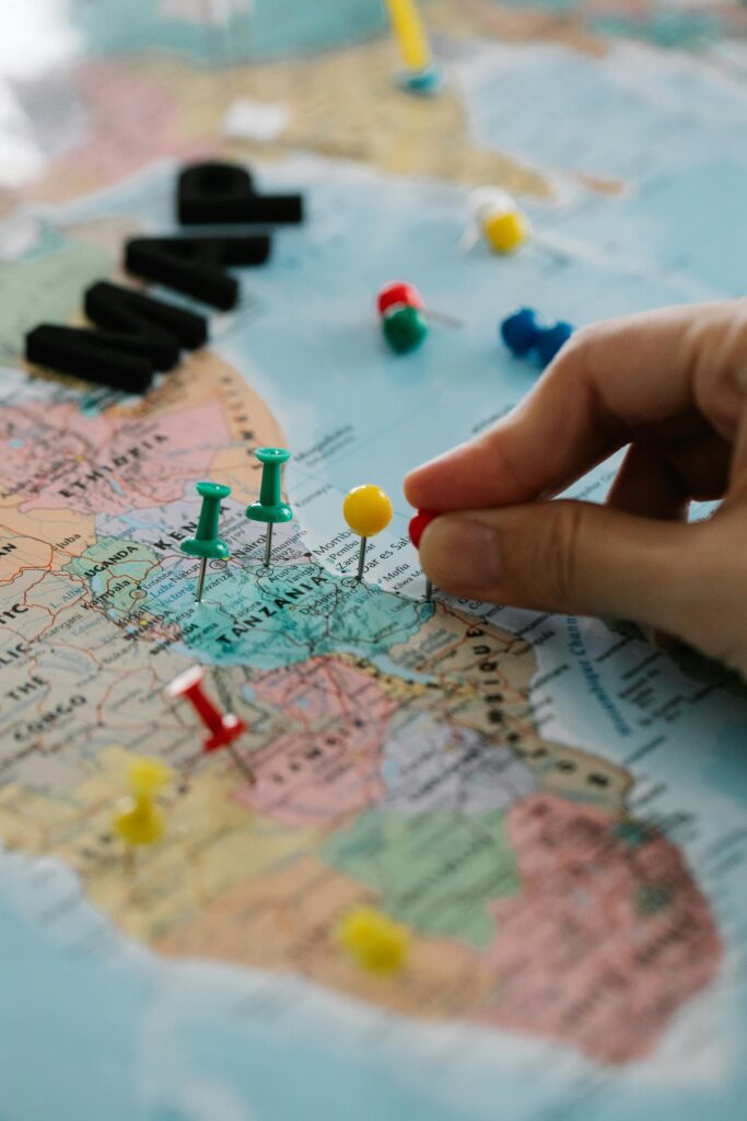 pexels-photo-8828427-8828427 Close-up of hand marking locations on a map with colorful pins, planning a journey.