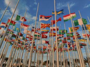 A diverse collection of national flags waving under a vibrant blue sky.